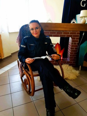 Policjantka siedząca w fotelu czytająca książeczkę