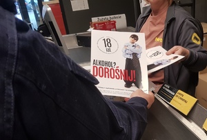 Policjant przekazujący ekspedientce ulotkę