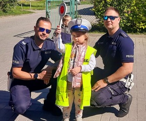 Policjanci wspólnie z przedszkolakiem w kamizelce i czapce policyjnej