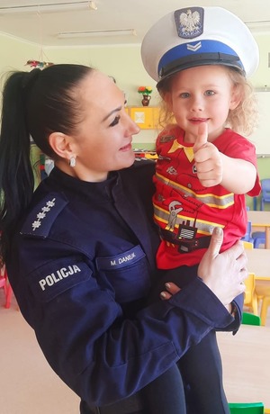 Policjantka trzymająca na rękach dziewczynkę w policyjnej czapce