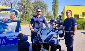 Policjanci z przedszkolakiem siedzącym na motorze