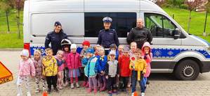 Policjanci w towarzystwie dzici na tle radiowozu