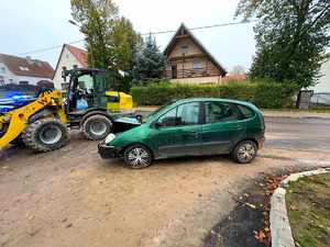 Miejsce zderzenia pojazdów. Uszkodzone zielone renault oraz stojąca obok koparko-ładowarka