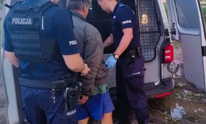 Poszukiwany mężczyzna osadzany przez policjantów w radiowozie