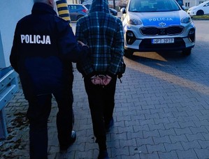 sprawca kradzieży w kajdankach prowadzony przez policjanta
