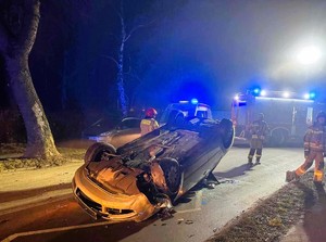 pojazd osobowy na dachu w oddali służby ratunkowe