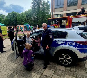 Policjanci podczas dni rodziny w towarzystwie dzieci obok radiowóz