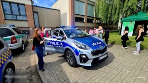 Policjanci podczas dni rodziny w towarzystwie dzieci obok radiowóz