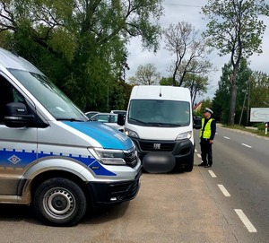 Policjant sprawdza stan trzeźwości kierującego białym busem