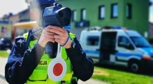 Policjant trzyma w rękach laserowy miernik prędkości