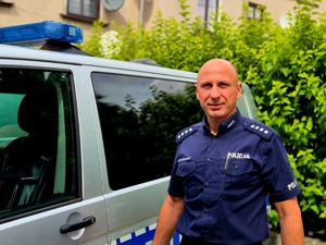 nadkom. Sławomir Pierzchanowski na tle radiowozu policyjnego