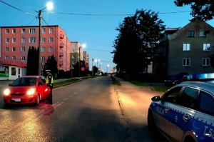 Badanie stany trzeźwości kierującego czerwonym autem wykonywane przez policjanta