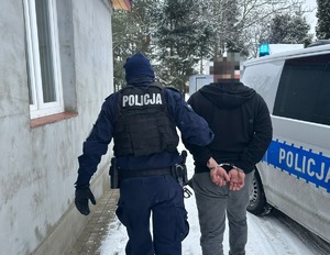Policjant prowadzi zatrzymanego mężczyznę