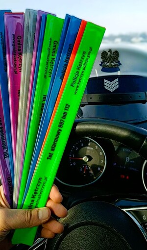 opaski odblaskowe trzymane w ręku w tle policyjna czapka